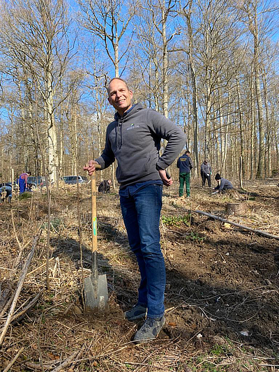 Vorstandvorsitzender Stephen Voss steht mit Spaten im Stadwald Usingen. 