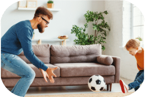 Junge schießt Fußball zu Papa im Wohnzimmer 